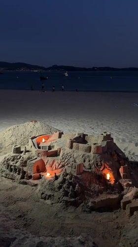 Candlelit sandcastle glows on a Galician beach at night