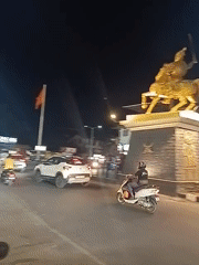 Golden horseman statue anchors busy Oxel traffic circle at night