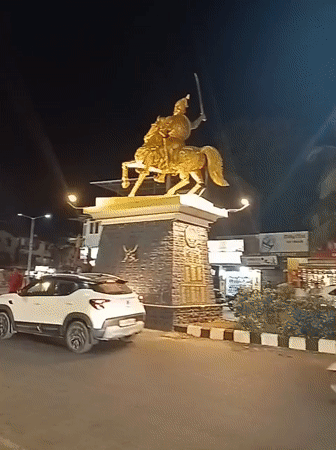 Golden horseman statue anchors busy Oxel traffic circle at night