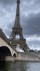 Seine River boat tourists view Eiffel Tower under clouds