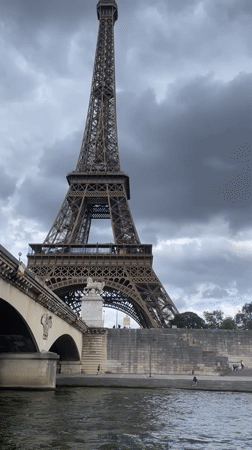 Seine River boat tourists view Eiffel Tower under clouds