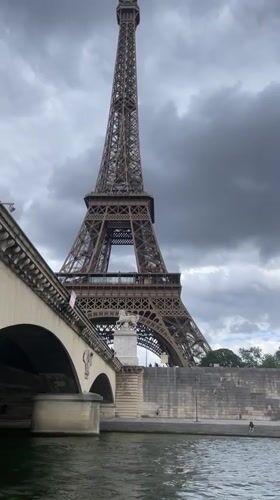 Seine River boat tourists view Eiffel Tower under clouds
