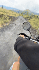 Motorcyclist rides dirt road in rural Kintamani, Indonesia
