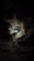 Dramatic moon illuminates cloudy night sky over Catania, Italy