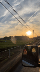 Driver captures sunset journey past urban farmland and infrastructure