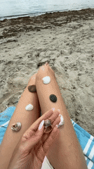 Woman collects seashells during beach visit in Ravda, Bulgaria