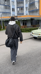 Man with bag approaches vintage car on street