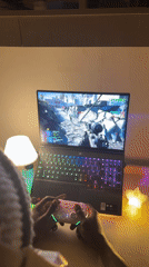 Gamer plays first-person shooter with colorful setup on wooden desk