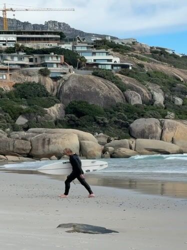 Surfers active at Hout Bay beach under cloudy skies