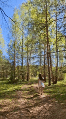 Woman in white dress photographed walking in Russian forest