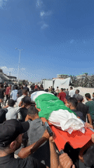 Funeral procession and armed presence in war-damaged Gaza streets