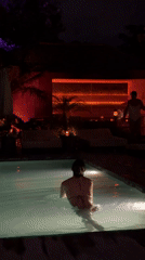 Woman swims in illuminated pool at night in Mengwi