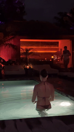 Woman swims in illuminated pool at night in Mengwi
