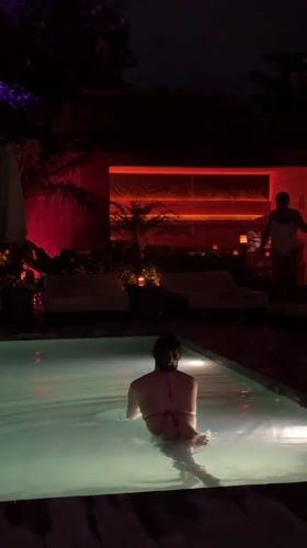 Woman swims in illuminated pool at night in Mengwi