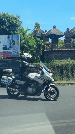 Police motorcycle stops behind SUV in Ubud, Indonesia