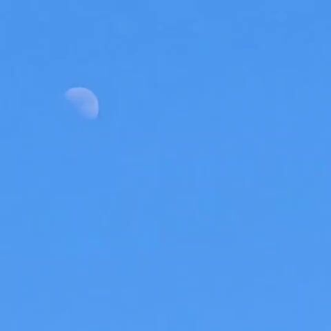 The video begins by showing the moon in a clear blue sky. The view then shifts to a modern building with a white and dark gray facade, featuring several windows. The sun then appears in the sky, shining brightly over the building's roof, which has an antenna and the text "ecosol" visible. The video concludes with a bright sun in a blue sky.