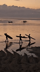 Dusk on a Denpasar beach — surfers, crowds, and calm water