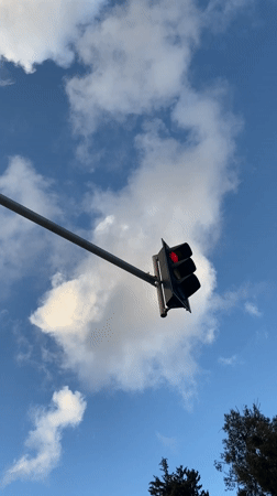 Red traffic light observed against blue sky in Haifa