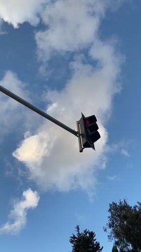 Red traffic light observed against blue sky in Haifa