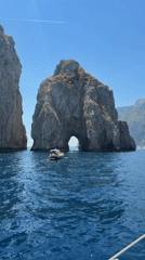 Boat passes through natural rock arch near Capri
