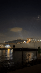 Ship Golden Bridge docked in Barcelona with upward light beams
