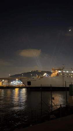 Ship Golden Bridge docked in Barcelona with upward light beams