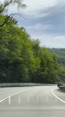 Vehicle travels wet roads through green Pshada countryside after rain