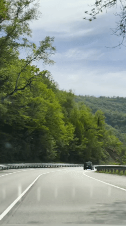Vehicle travels wet roads through green Pshada countryside after rain