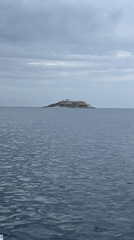 Motorboat speeds across Montenegro waters near island building