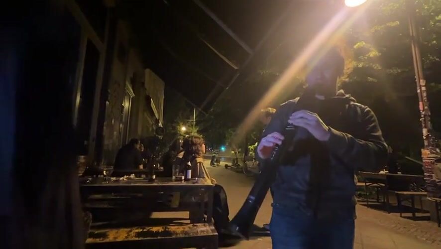 Musician plays electronic wind instrument in nighttime Berlin performance