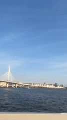 Waterfront scenes captured near cable-stayed bridge on clear afternoon
