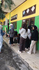 Group rehearses outside a yellow and green building