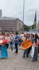 Crowd gathers with signs, balloons in Dortmund square celebration
