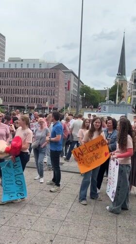 Crowd gathers with signs, balloons in Dortmund square celebration