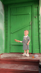 Toddler plays in rural Russian yard with grandfather
