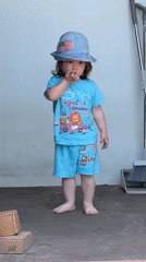 Toddler plays barefoot in sunny Gudauta garden amid flowering plants