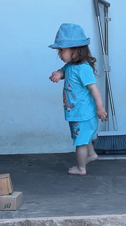 Toddler plays barefoot in sunny Gudauta garden amid flowering plants