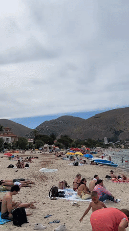 Crowded beach day at Palermo's Mondello under cloudy skies