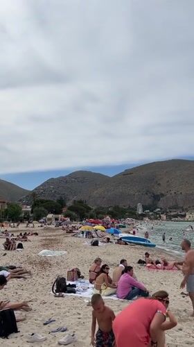 Crowded beach day at Palermo's Mondello under cloudy skies