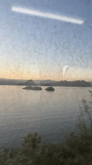 Train passenger views serene lake with islands near Vranjina