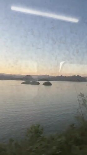 Train passenger views serene lake with islands near Vranjina
