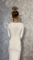Woman models white dress with archer design in Abakan home