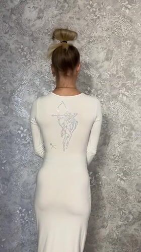 Woman models white dress with archer design in Abakan home