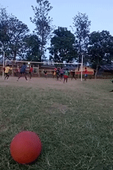 Community volleyball game played on grass field in Kenya