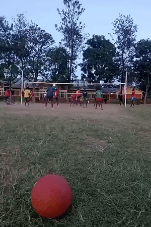 Community volleyball game played on grass field in Kenya