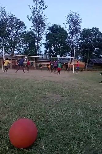Community volleyball game played on grass field in Kenya