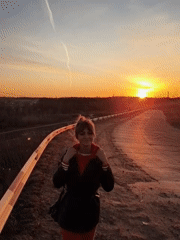 Woman stands by roadside guardrail during sunset in Chaikovsky