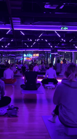 Group practices yoga in purple-lit studio