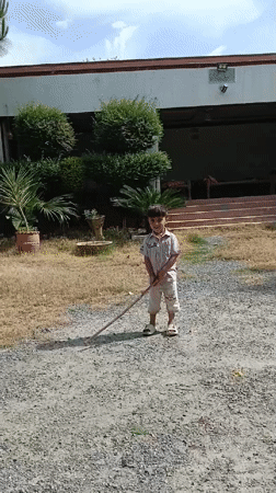 Child plays improvised cricket in Pakistani village driveway