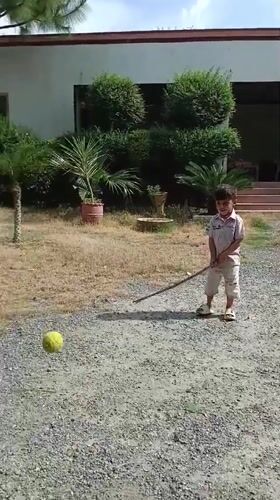Child plays improvised cricket in Pakistani village driveway
